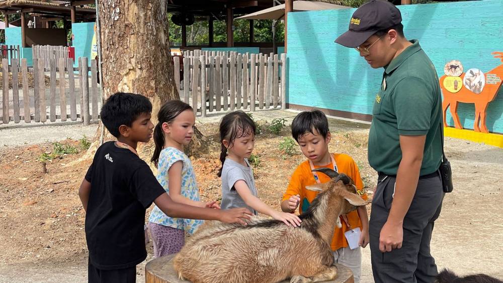 Zookeeper and 4 children petting a goat